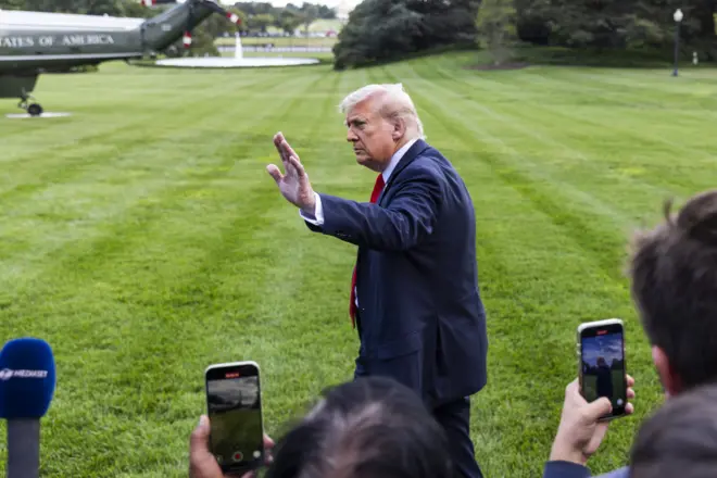 Трамп махає рукою на прощання журналістам, розвертаючись від них у напрямку свого гелікоптера на галявині перед Білим домом