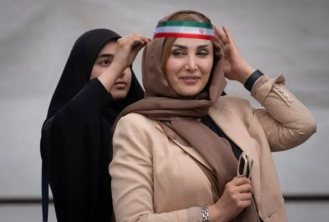 A veiled pro-government supporter wears an Iranian national flag after a ceremony to commemorate civilians and military personnel who were killed during military operations involving the United States and Israel, at the Imam Khomeini Grand Mosque in downtown Tehran, Iran, on May 24, 2026.