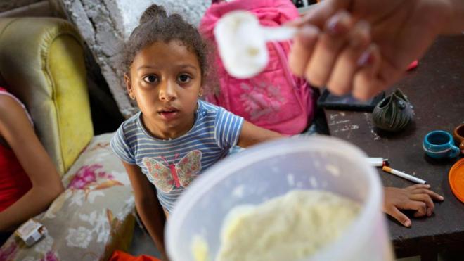 Criança olhando para recipiente com leite em pó em Cuba