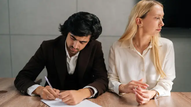 Una pareja infeliz firmando un acuerdo de divorcio