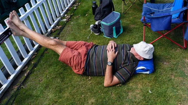 Homem descansando com pés apoiados em cerca