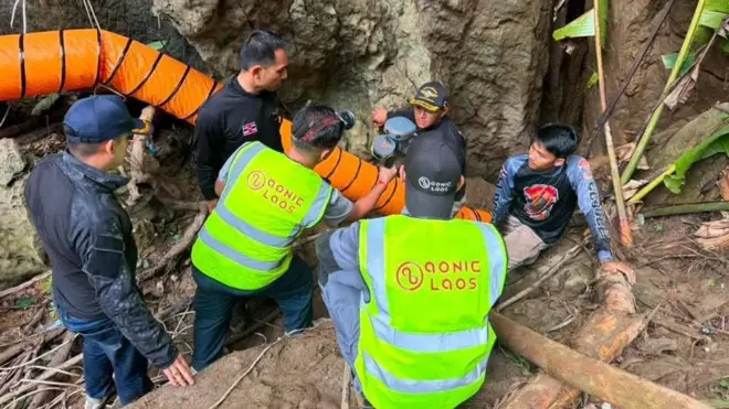 Rescuers trying to fix an orange pump onto one of the cave's entrances
