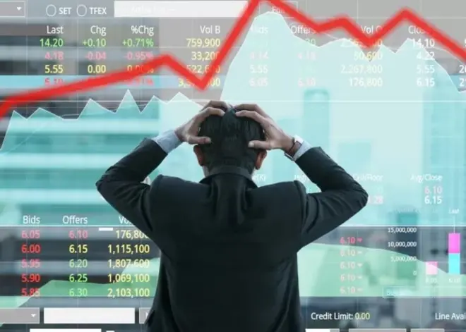 Un homme, les mains sur la tête, observe le cours des actions à la bourse