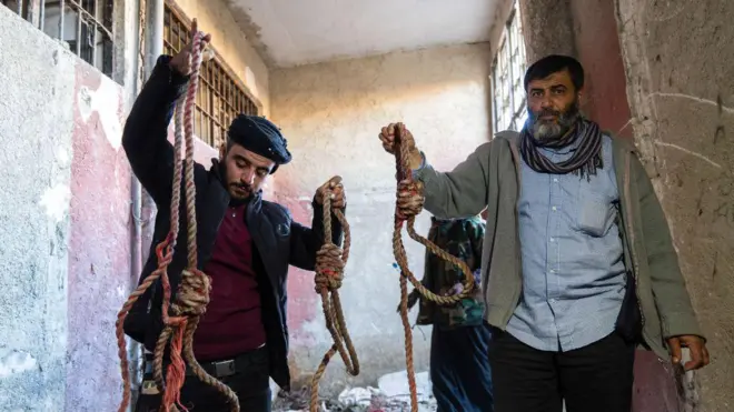 أشخاص داخل سجن صيدنايا يحملون حبال الإعدام مليئة بالدماء