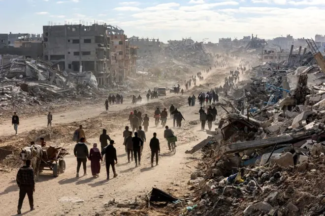 20 Ocak 2025'te Gazze Şeridi'nin kuzeyindeki Cibaliye'deki Saftawi Caddesi boyunca insanlar yıkılmış binaların enkazının arasından yürüyor.
