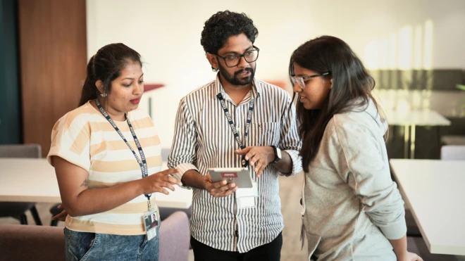 කාර්යාලය කතා බස් කරමින් සිටින සේවකයින් තිදෙනෙකුගේ ඡායාරුපයකි