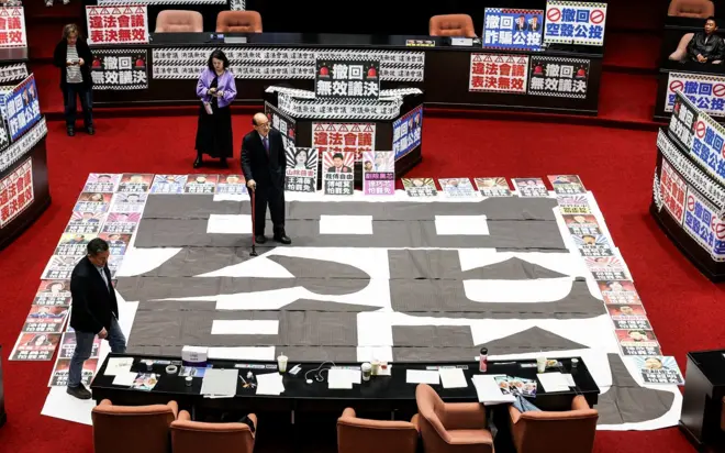 2025年3月28日，执政民进党立委柯建铭站在立法院一张写有“罢免”字样的海报上