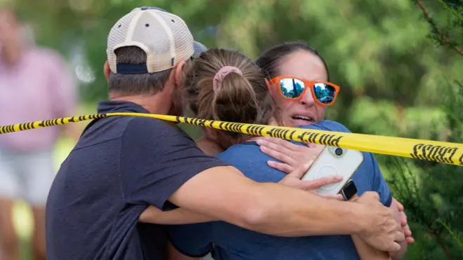 Benewabo n'abishwe barimo guhozanya bahoberanye hanze y'uruzitiro rw'umutekano rwa polisi, nyuma y'iraswa ryabereye kuri Kiliziya yitwa Annunciation Church. 