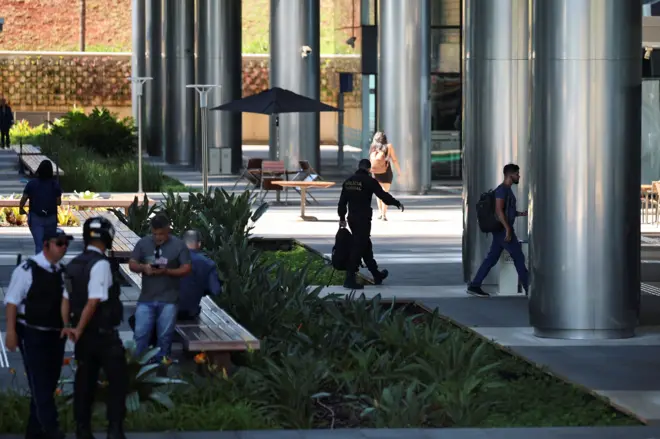 Um agente da Polícia Federal caminha próximo à entrada do BRB, Banco de Brasília, durante uma operação contra a emissão fraudulenta de títulos de crédito por instituições financeiras, que resultou na prisão de Daniel Vorcaro, em Brasília, Brasil, 18 de novembro de 2025