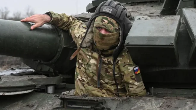 یک سرباز با صورتی پوشیده تا نیمه از تانک بیرون آمده