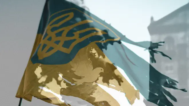 Експозиція білого голуба миру над розірваним українським прапором