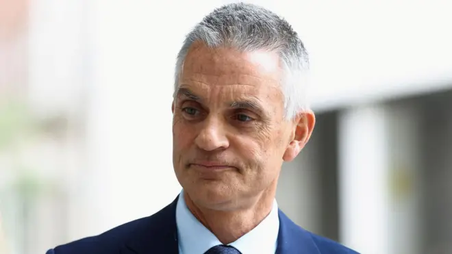 Gros plan sur Tim Davie, directeur général de la BBC, vêtu d'un costume bleu marine