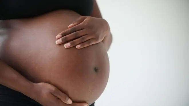 A pregnant woman holding her baby bump