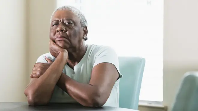 Une femme noire vieillissante regarde sérieusement la caméra