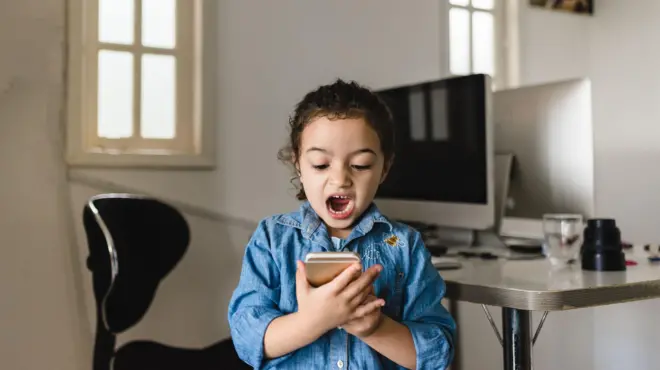 طفلة تنظر إلى هاتفها المحمول باندهاش