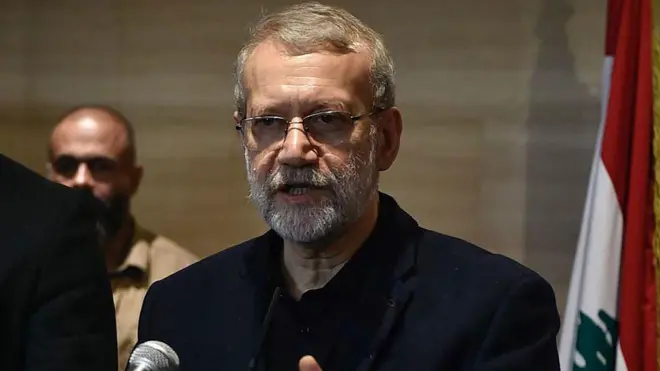 Alí Larijani, vestido de oscuro, con barba y gafas, delante de un micrófono