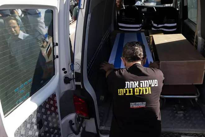Homem inclinado sobre caixão com bandeira de Israel 