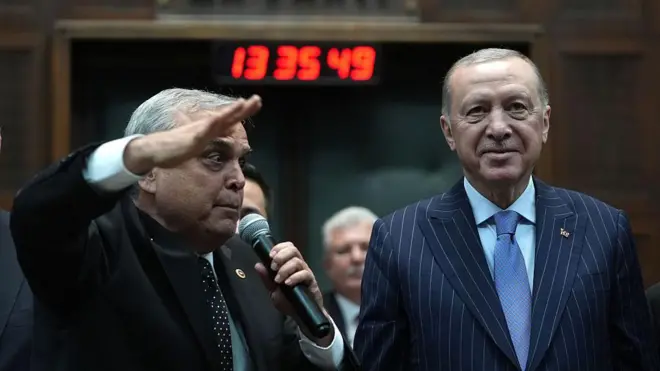 Erdoğan'ın yanındaki eski CHP'li vekil, selam duruyor. Erdoğan ileri bakarak tebessüm ediyor.