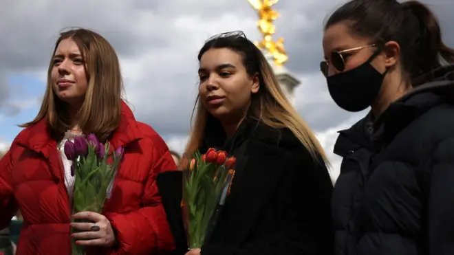 Members of the public hold flowers outside Buckingham Palace