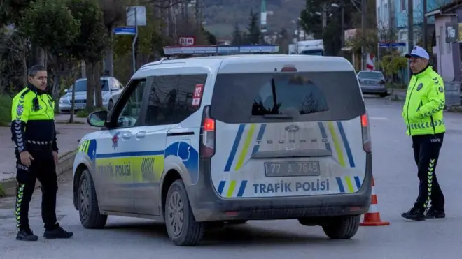 فردان من قوات الأمن التركية يقفان بجوار سيارة شرطة تغلق الشارع أثناء تنفيذ مداهمة أمنية في يالوفا