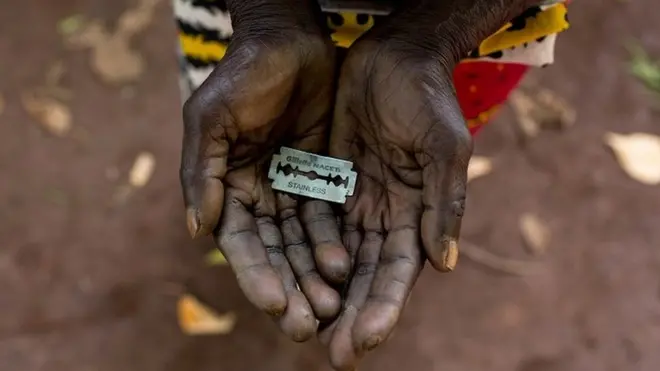 A cupped pair of hands holding a razorblade