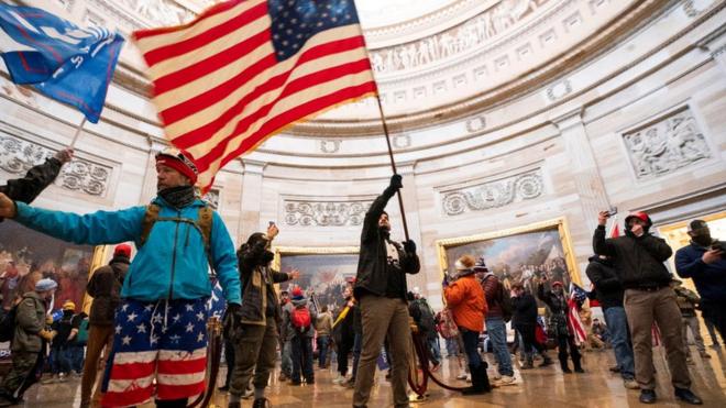 Protesters fill the Rotunda of the US Capitol building waving a US flag