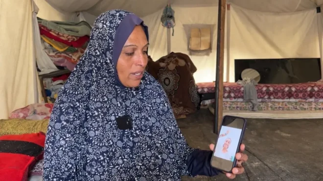 لینا ضبع که در چادر زندگی می‌کند روی موبایل تصویری از دخترش آیه را نشان می‌دهد
