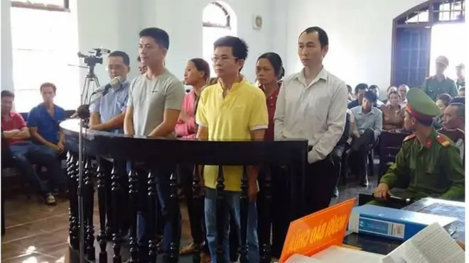 Ông Trần Minh Lợi (áo vàng) và các bị cáo tại phiên tòa hôm 22/3