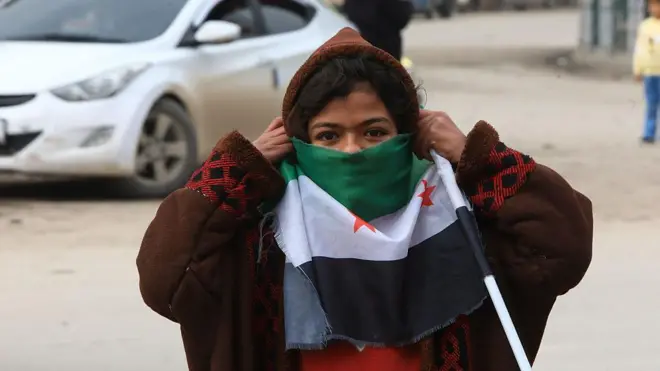 Suriye yönetiminin Rakka'nın kontrolünü SDG'den geri almasının ardından, 28 Ocak'ta üç yıldızlı Suriye bayrağıyla sokakta yürüyen bir kız çocuğu,