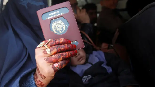 یک زن افغان در حالیکه پاسپورت خود را حمل می کند 