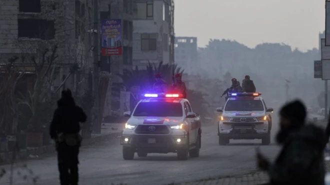 Halep'te hükümet güçleri devriye araçlarında görülüyor. Gezdikleri caddedeki binaların yıkıntı halinde olduğu da görülüyor.