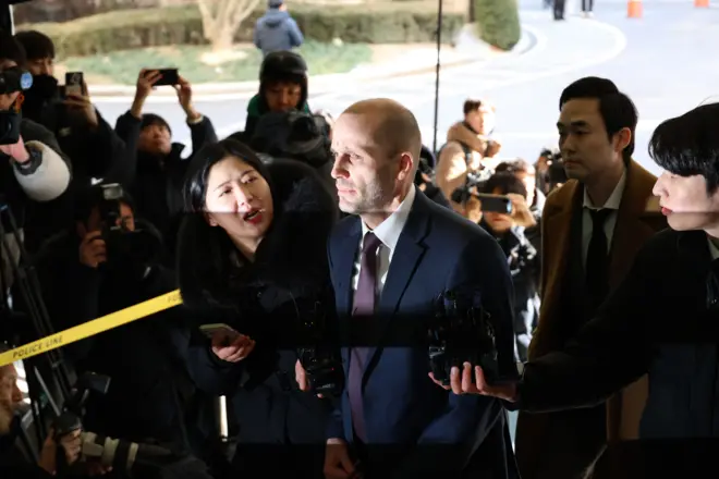 해럴드 로저스 쿠팡 한국 법인 임시대표가 취재진에 둘러싸인 채 질문을 받고 있으며 주변에는 카메라와 녹음 장비를 든 기자들이 모여 있다