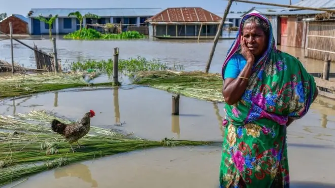Umugore uhagaze mu muhanda urimo imyuzure muri Bangladesh.