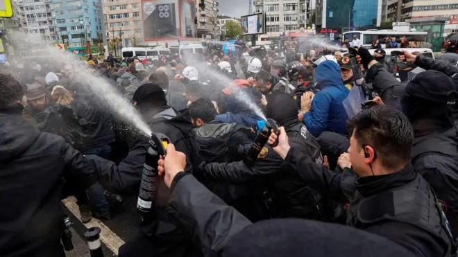 Polis kalabalık bir gruba doğru biber gazı sıkıyor. 