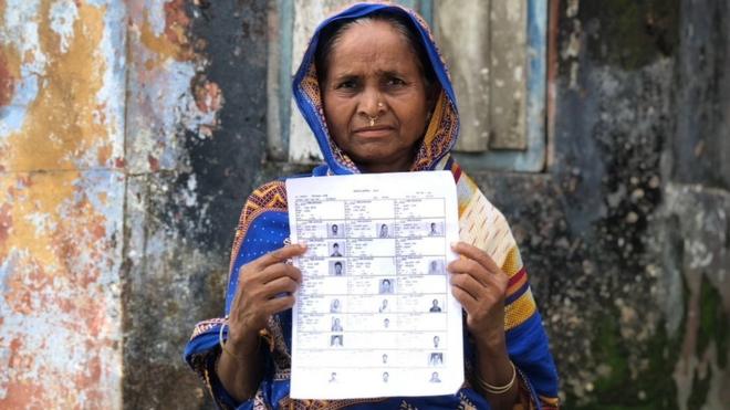A woman holds up a draft list of the National Citizen's Register in Assam