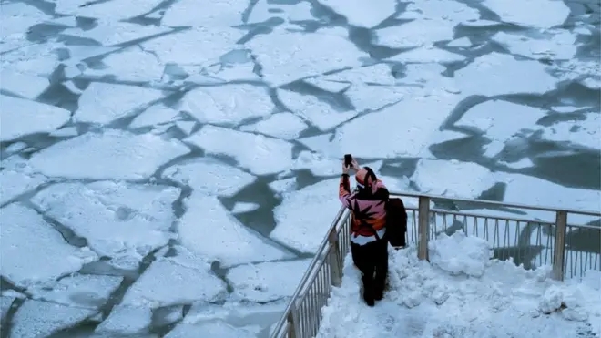 Seorang warga memotret Sungai Chicago yang membeku akibat fenomena alam yang disebut polar vortex.