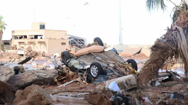 ডেরনা শহরে ধ্বংসস্তুপের মধ্যে গাড়ী দেখা যাচ্ছে