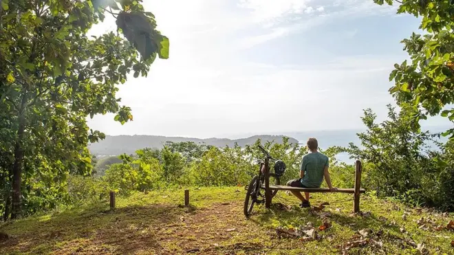 Un homme assis sur un banc regardant le paysage qui s'offre à lui.