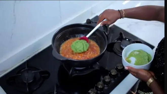 Aworan ọwọ to n fa cucumber lilọ sinu ata lori ina