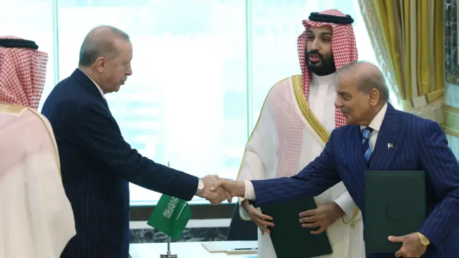 الرئيس التركي رجب طيب أردوغان (الثاني من اليسار)، وولي العهد السعودي الأمير محمد بن سلمان (في الوسط)، ورئيس الوزراء الباكستاني شهباز شريف (على اليمين) خلال توقيع اتفاقية مكة للدفاع المشترك في مكة المكرمة في المملكة العربية السعودية في 7 أغسطس/آب 2026.
