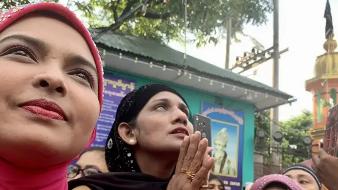 میانمار سے تعلق رکھنے والی دو خواتین علم کشائی کے دوران دعا مانگ رہی ہیں