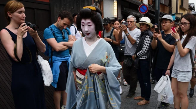 Wisatawan mengambil foto seorang geiko berjalan melalui kawasan Gion di Kyoto, Jepang, pada Kamis, 28 Mei 2015.