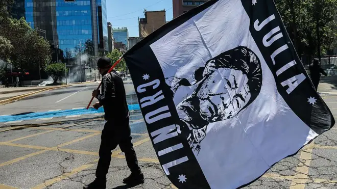 Un manifestante sostiene una bandera con el rostro de Julia Chuñil.