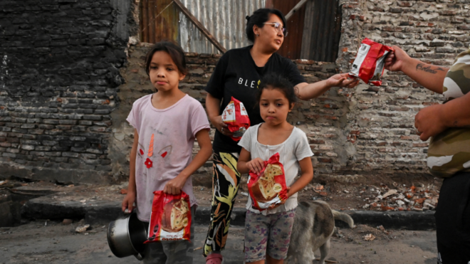 Uma família recebe pão doce em um refeitório em Villa Fiorito, Buenos Aires