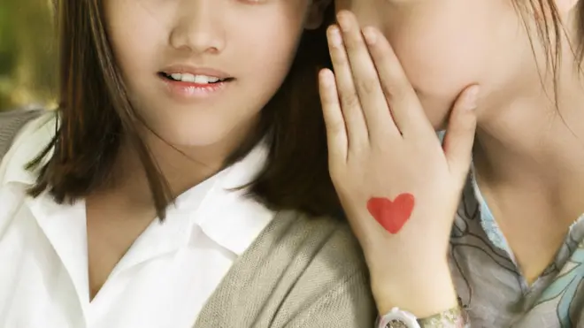 فتاة تهمس إلى صديقتها