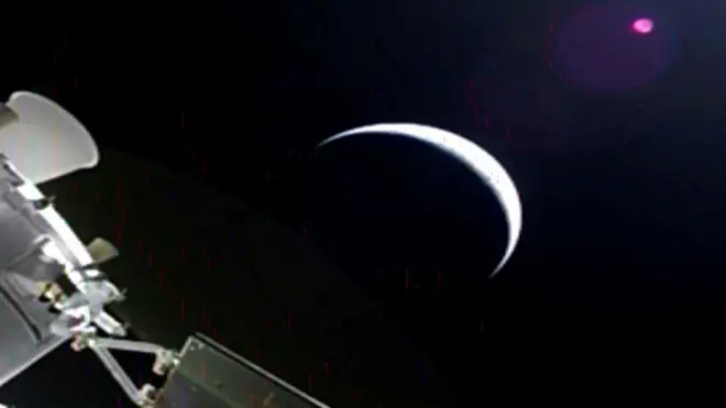 A sliver of the moon and parts of the orion spacecraft off to the side.