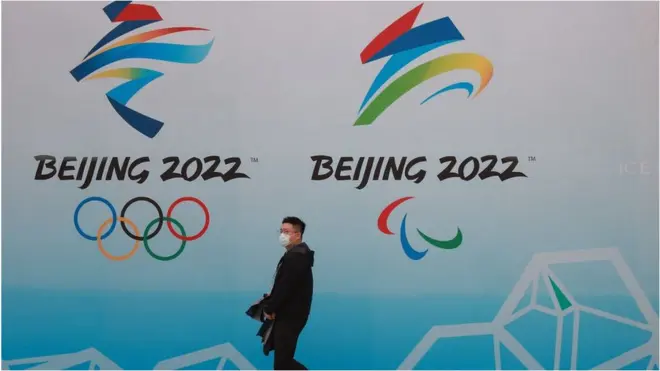 A man walks past a Beijing Olympics sign