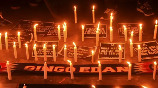 Lit candles are left as a tribute to the victims of the football disaster in Indonesia