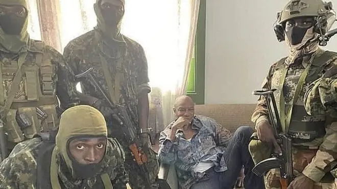 Стоп-кадр з відео, яке поширюється в гвійнейських соцмережах. Альфа Конде на ньому оточений озброєними військовими, говорить лише кілька слів, а решту часу сидить з відчуженим виглядом