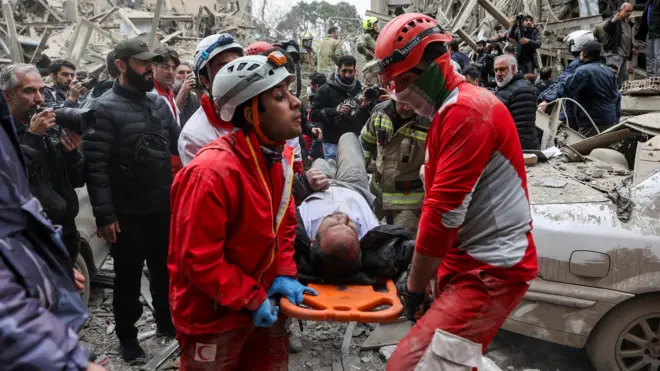 спасатели с пострадавшим на месте разрушенного авиаударом дома в Тегеране